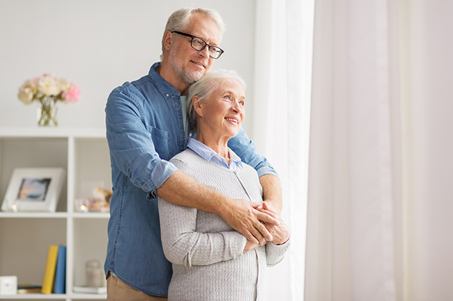 happy senior couple looking through window at home